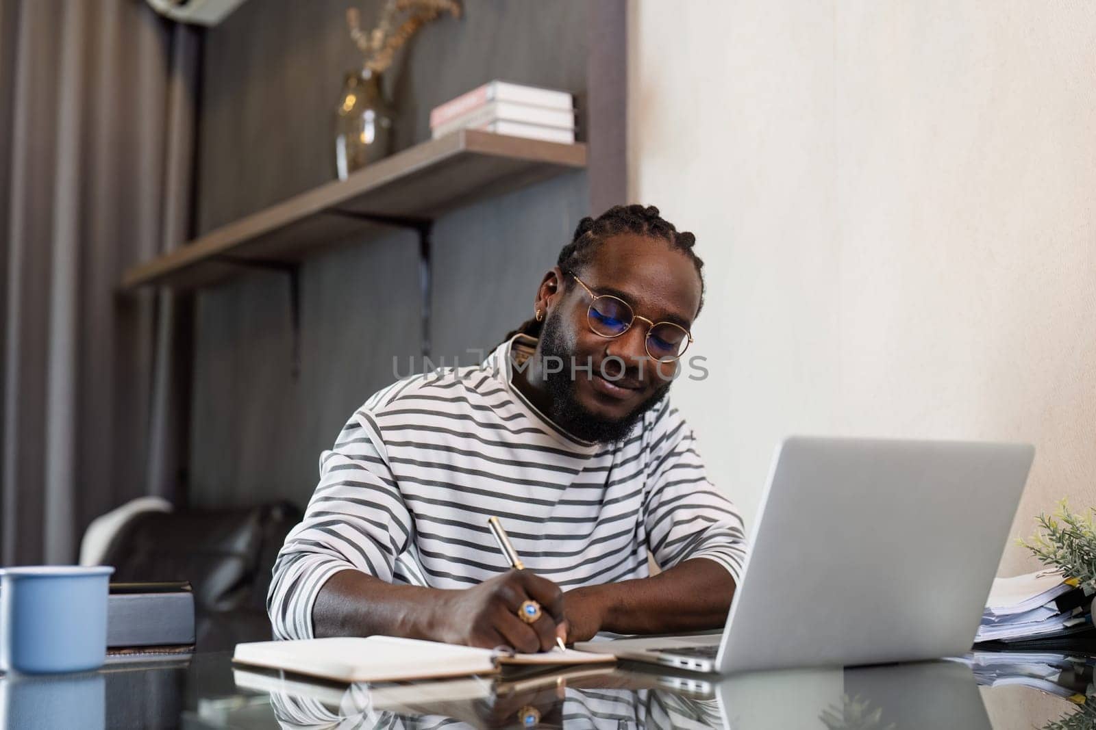 Young African American business man working with laptop and document on desk at home. work from home concept.