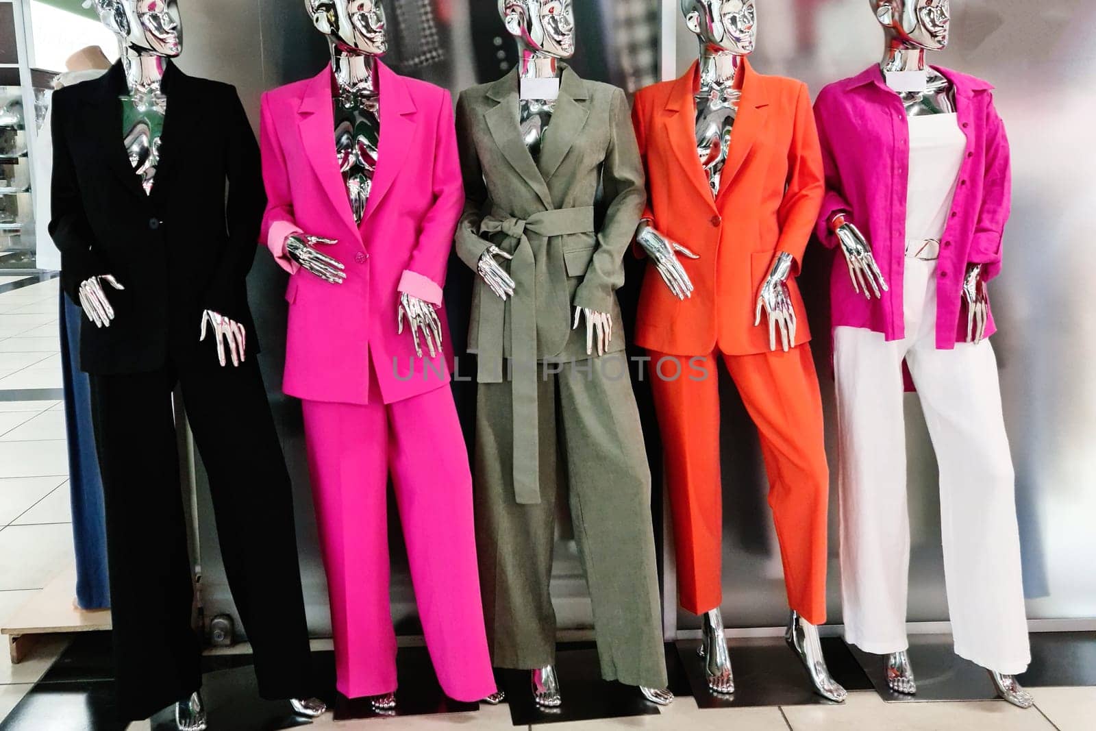 Colorful women's clothing in a boutique is worn on mannequins.