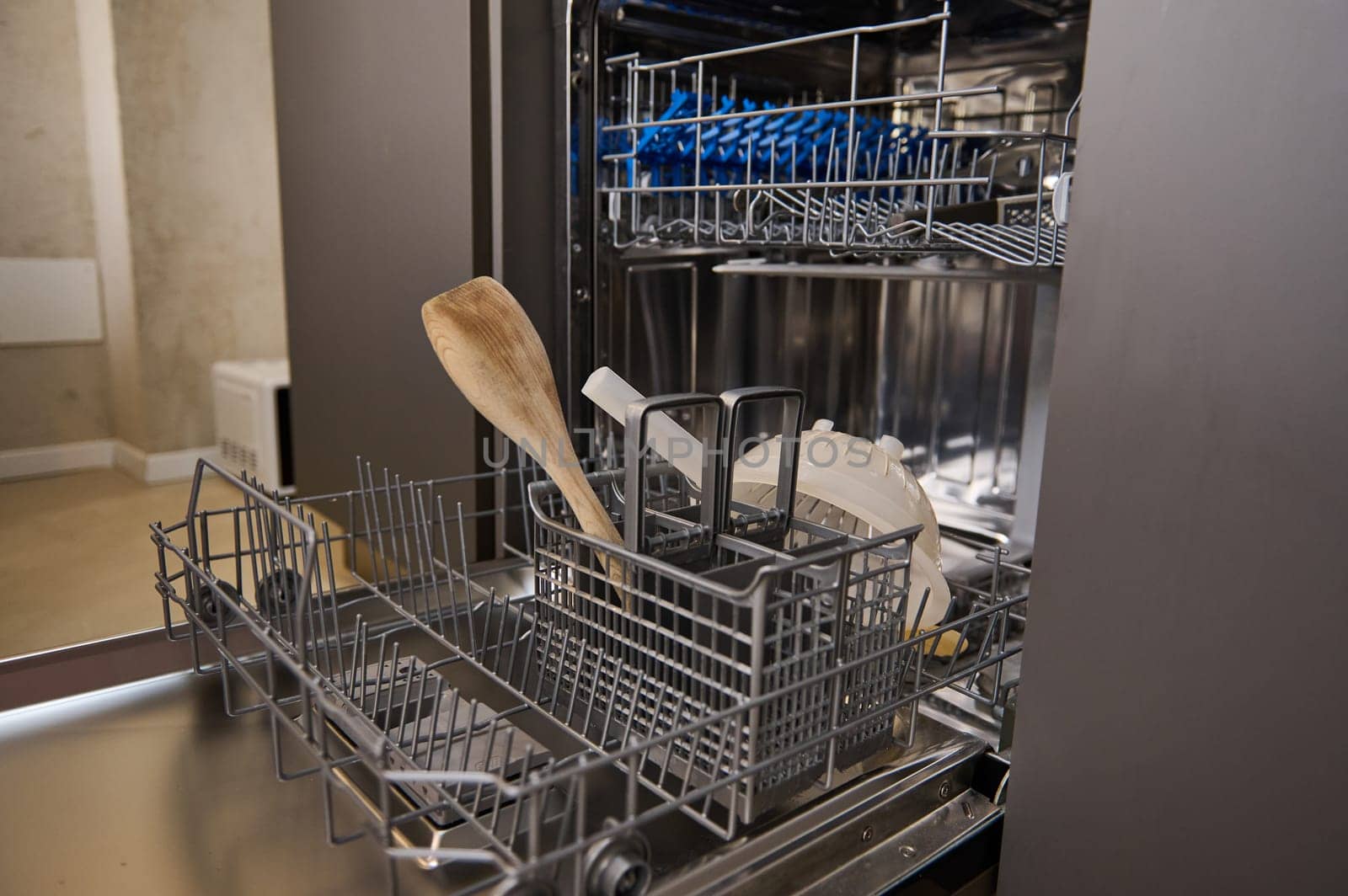 Close-up view of an open empty automatic dishwasher in kitchen. Modern kitchen appliance. Housekeeping equipment, Household chores.