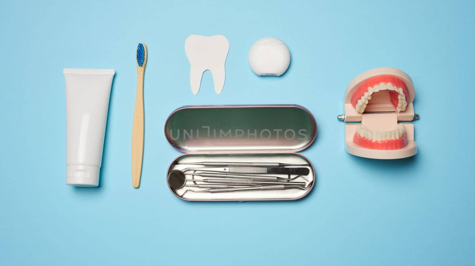 Mouthwash, toothpaste tube, dental floss and medical mirror on a blue background, oral hygiene.  by ndanko