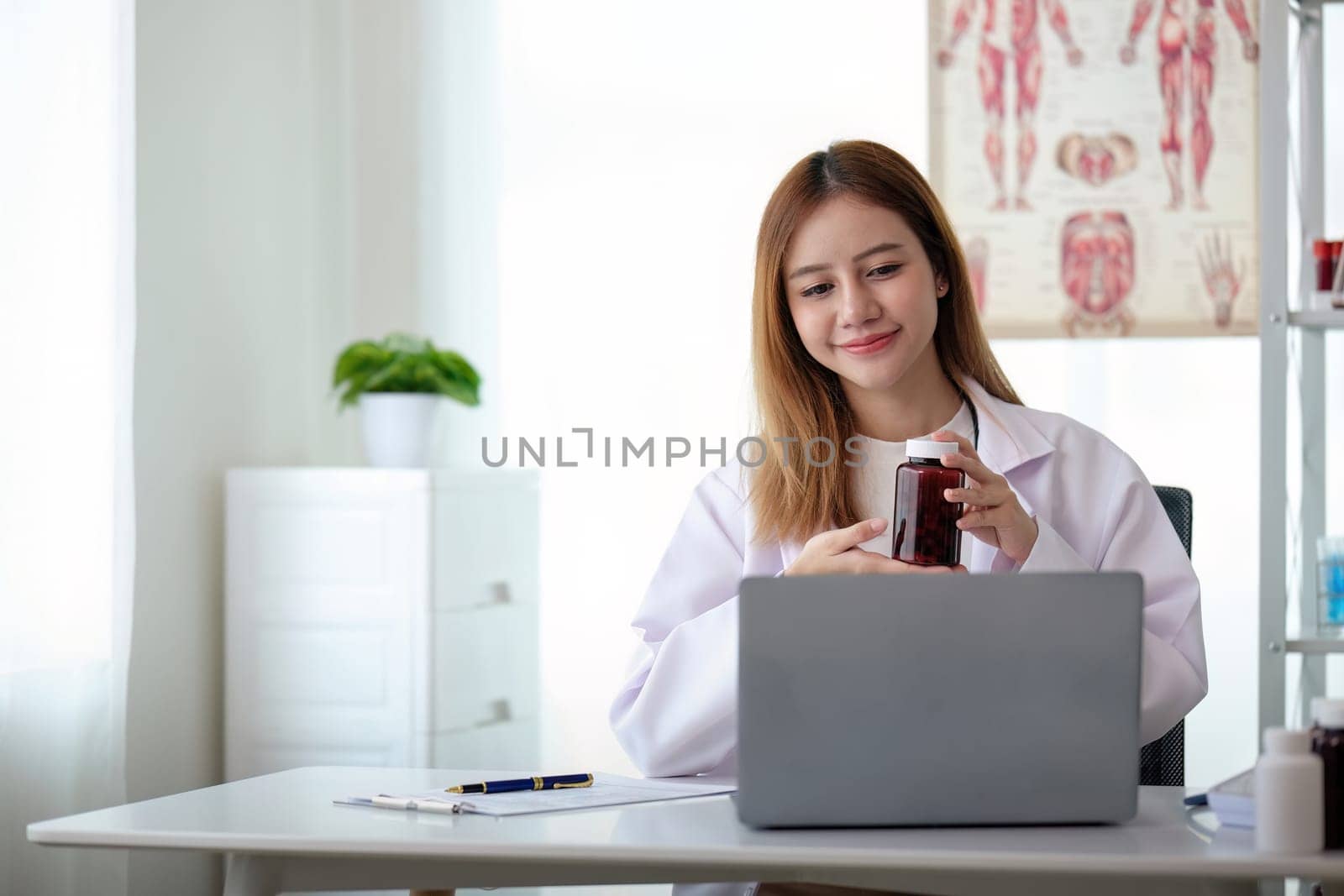 Young woman asia doctor with stethoscope using computer laptop talking video conference call with patient at desk in health clinic or hospital. Consulting and therapy concept.