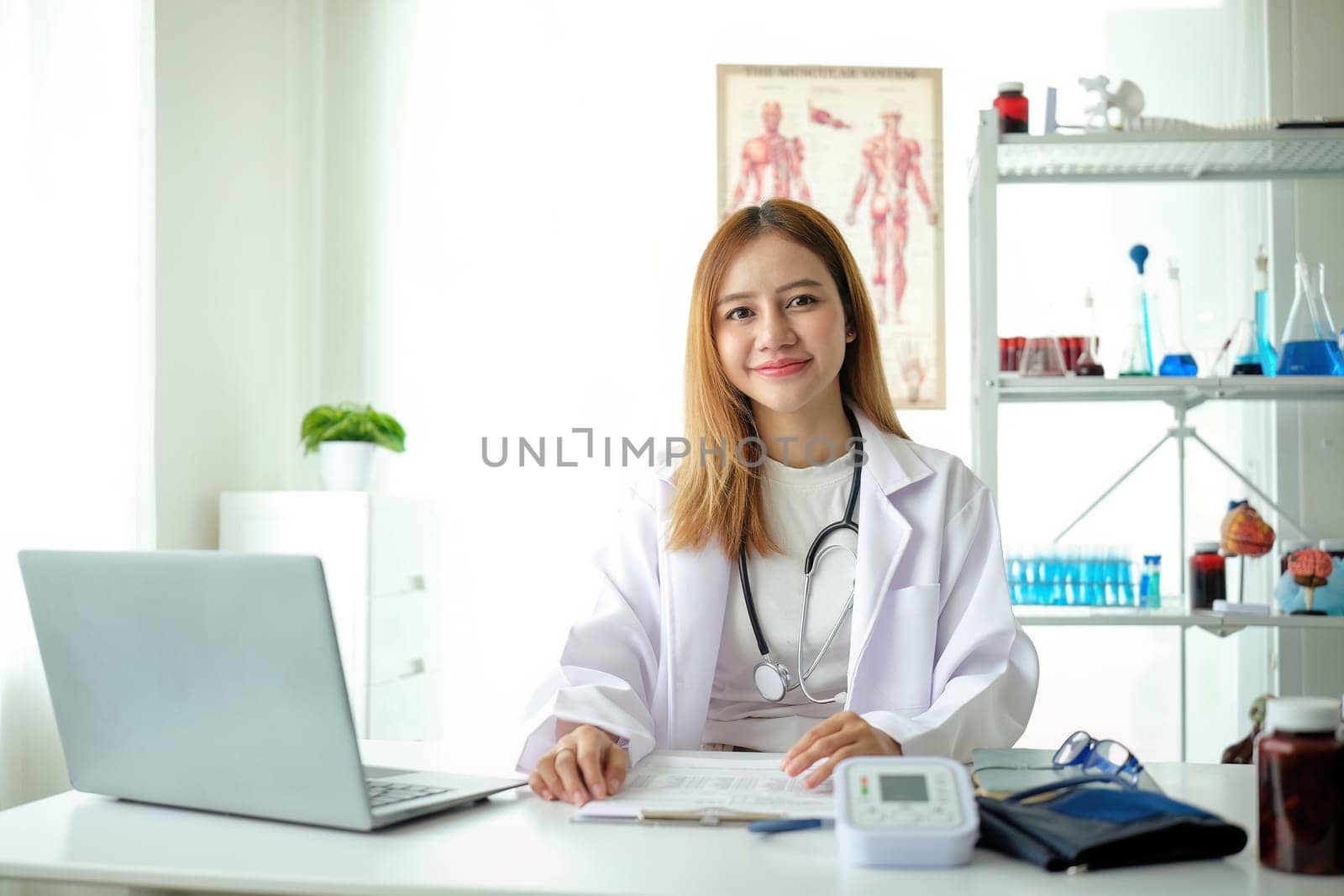 Female doctor working on laptop at office desk at in health clinic or hospital by nateemee