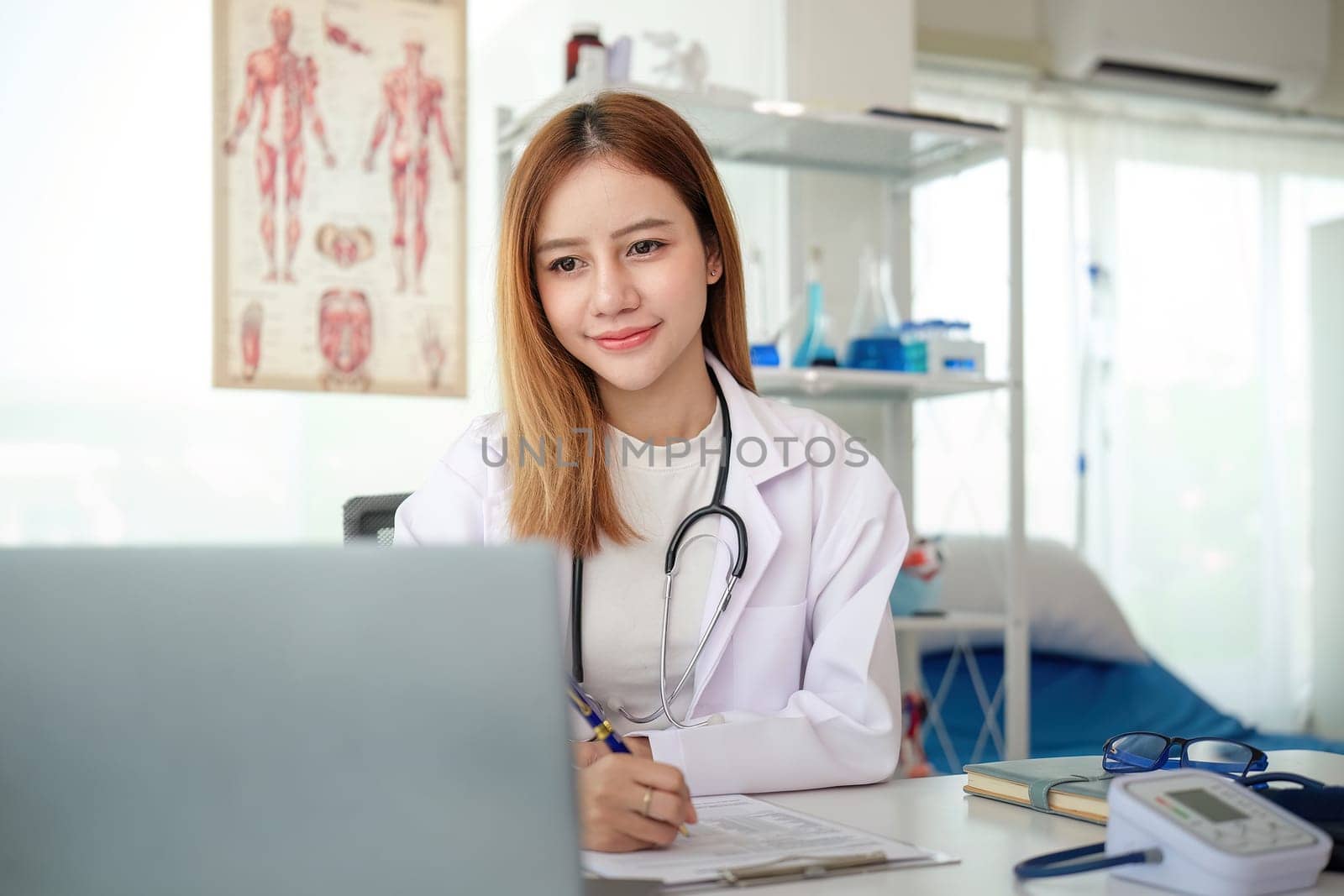 Female doctor working on laptop at office desk at in health clinic or hospital by nateemee