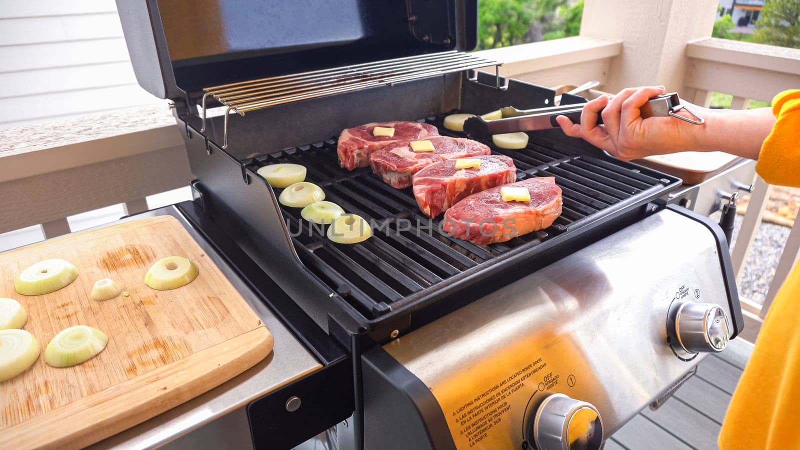 The outdoor two-burner gas grill is put to good use, sizzling with the sound and aroma of ribeye steaks and onion rings being perfectly cooked.