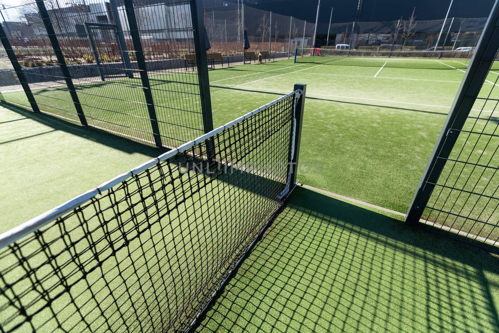 Landscaped areas of a residential development with a tennis court with high Plexiglas and metal fences. High quality photo