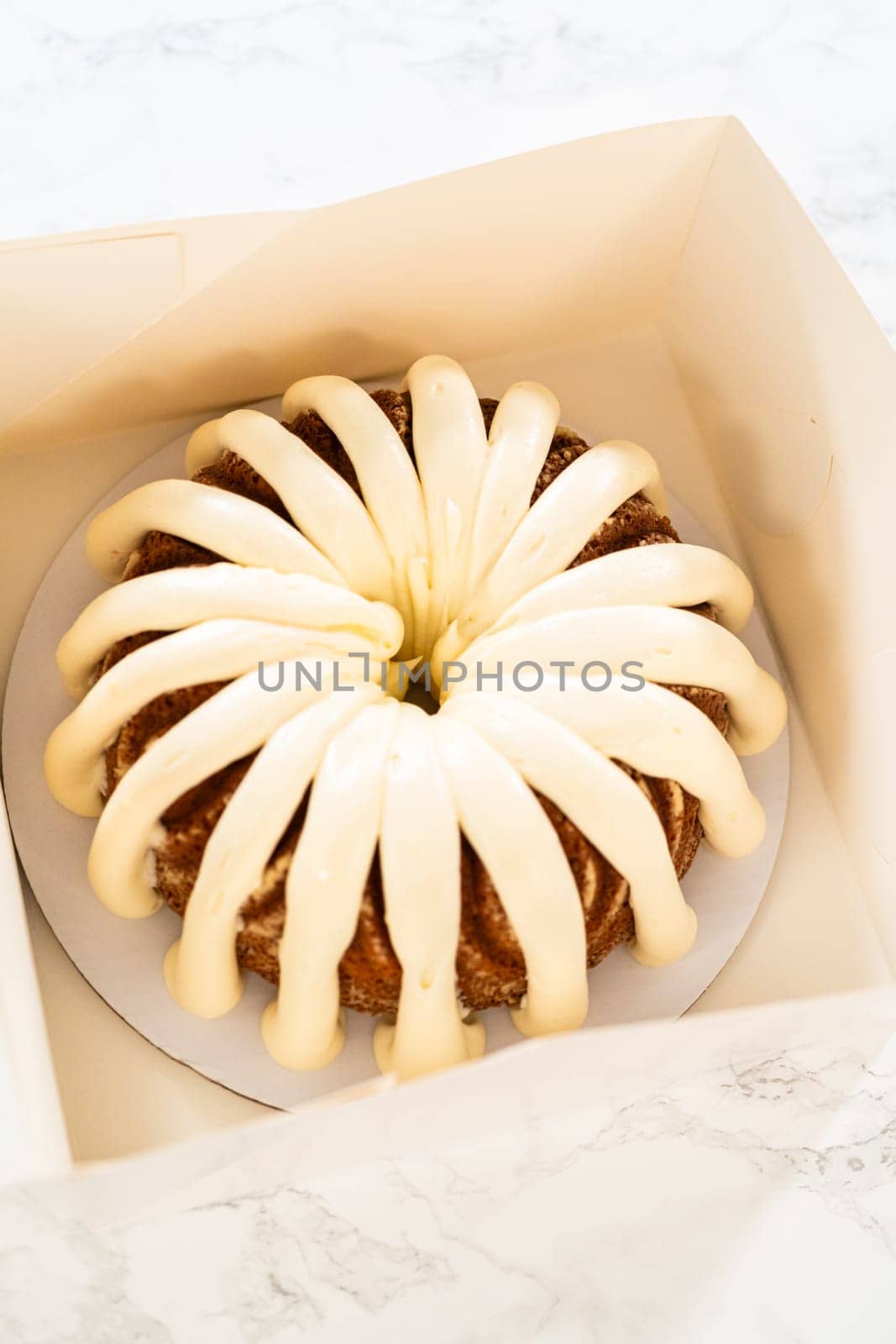 The freshly baked bundt cakes are carefully nestled into white paper boxes, preparing them for secure transportation while maintaining their delectable appearance.