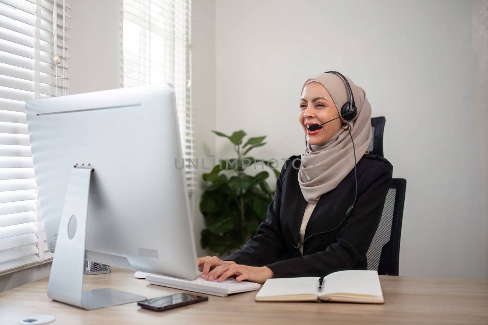 Young muslim women wearing hijab telemarketing or call center agent with headset working on support hotline at office by nateemee