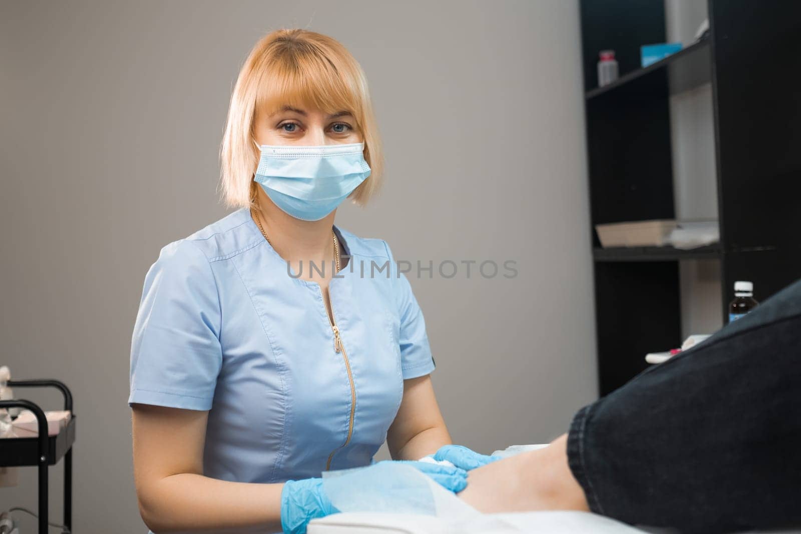 Portrait of podologist podiatrist in face mask and uniform at the clinic by vladimka