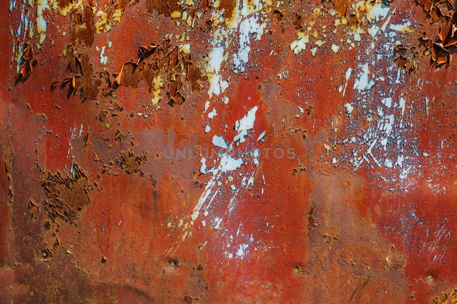 Closeup of rusty metal with peeling brown paint under direct sun light, full-frame background and texture.