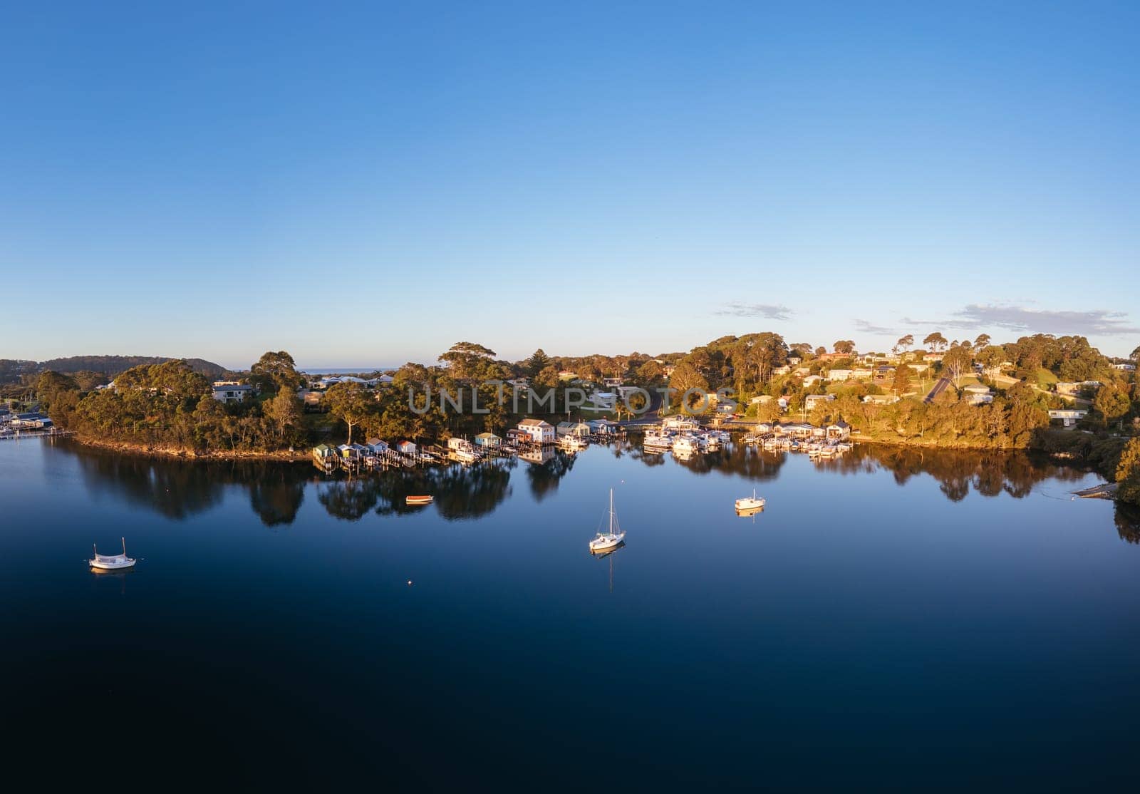 Aerial view of the idyllic coastal town of Narooma at sunset wrapped around the famous Wagonga Inlet in South Coast, New South Wales, Australia