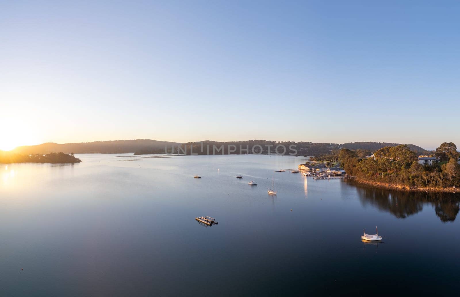 Aerial view of the idyllic coastal town of Narooma at sunset wrapped around the famous Wagonga Inlet in South Coast, New South Wales, Australia