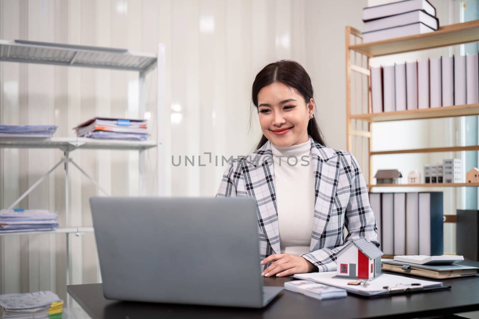 Real estate agent working with laptop at table in office.