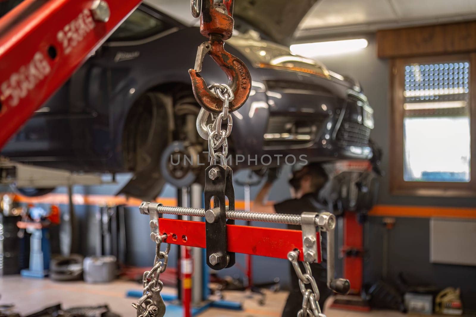 Close-up of an engine being hoisted by a chain in a workshop, emphasizing auto repair service.