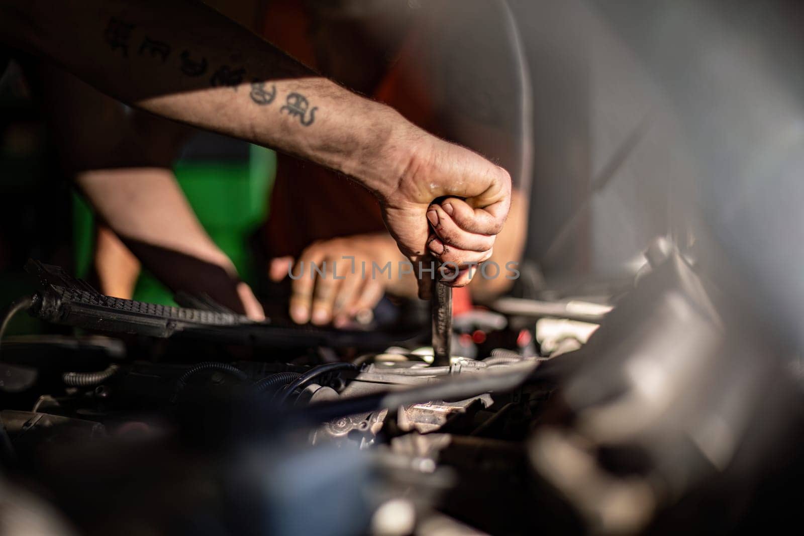 Close-up of a mechanic's dirty hands while repairing a car engine, showcasing hard work.