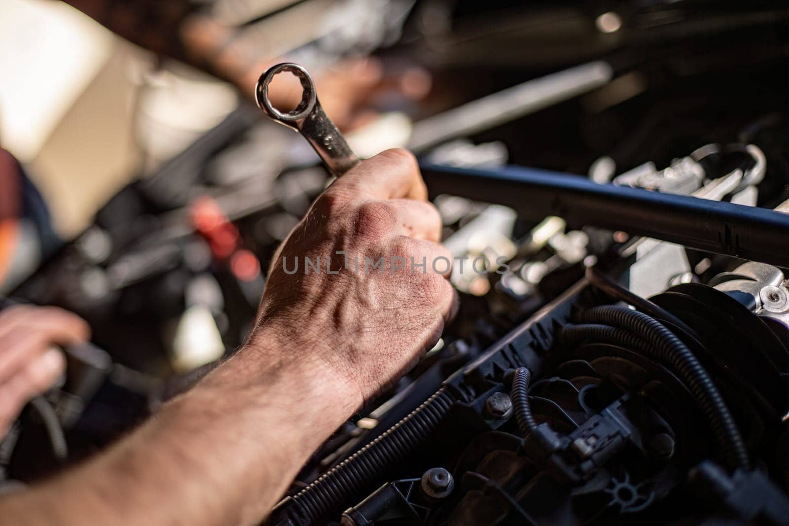 Close-up of a mechanic's dirty hands while repairing a car engine, showcasing hard work.