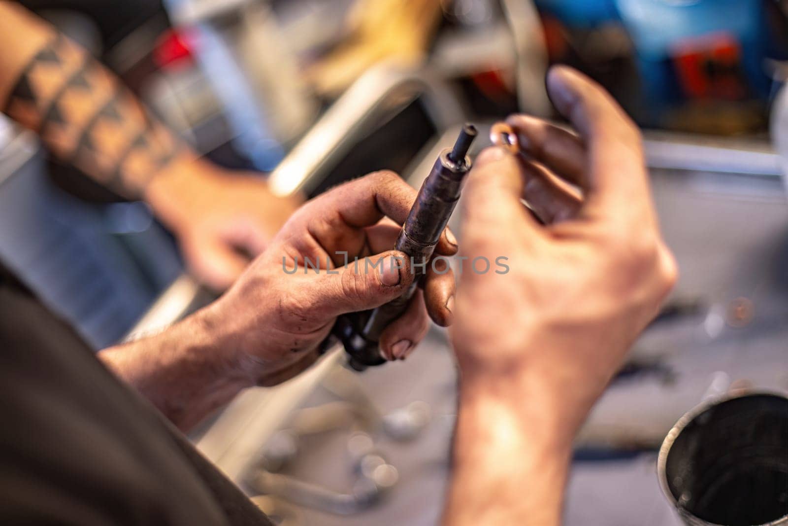 Close-up of a mechanic’s dirty hands holding a diesel engine injector, focus on repair work.