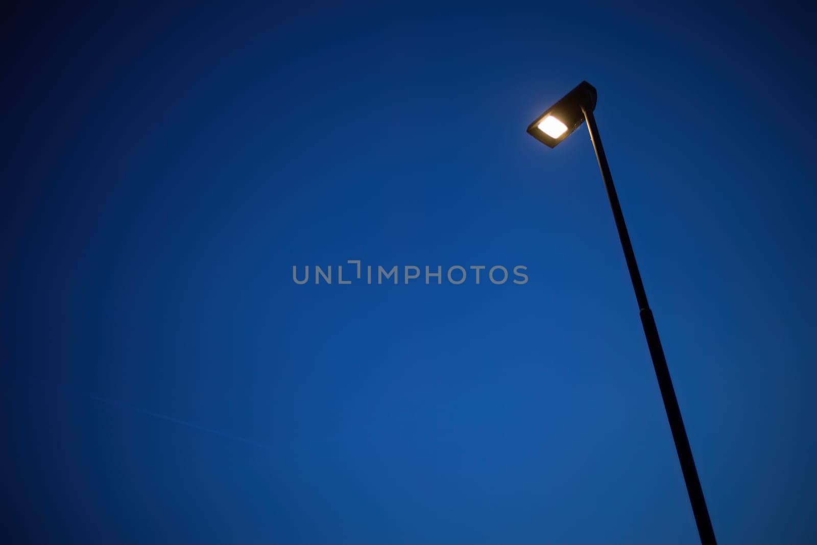 A lone street lamp casts a warm glow on the surrounding darkness, symbolizing solitude and peace.