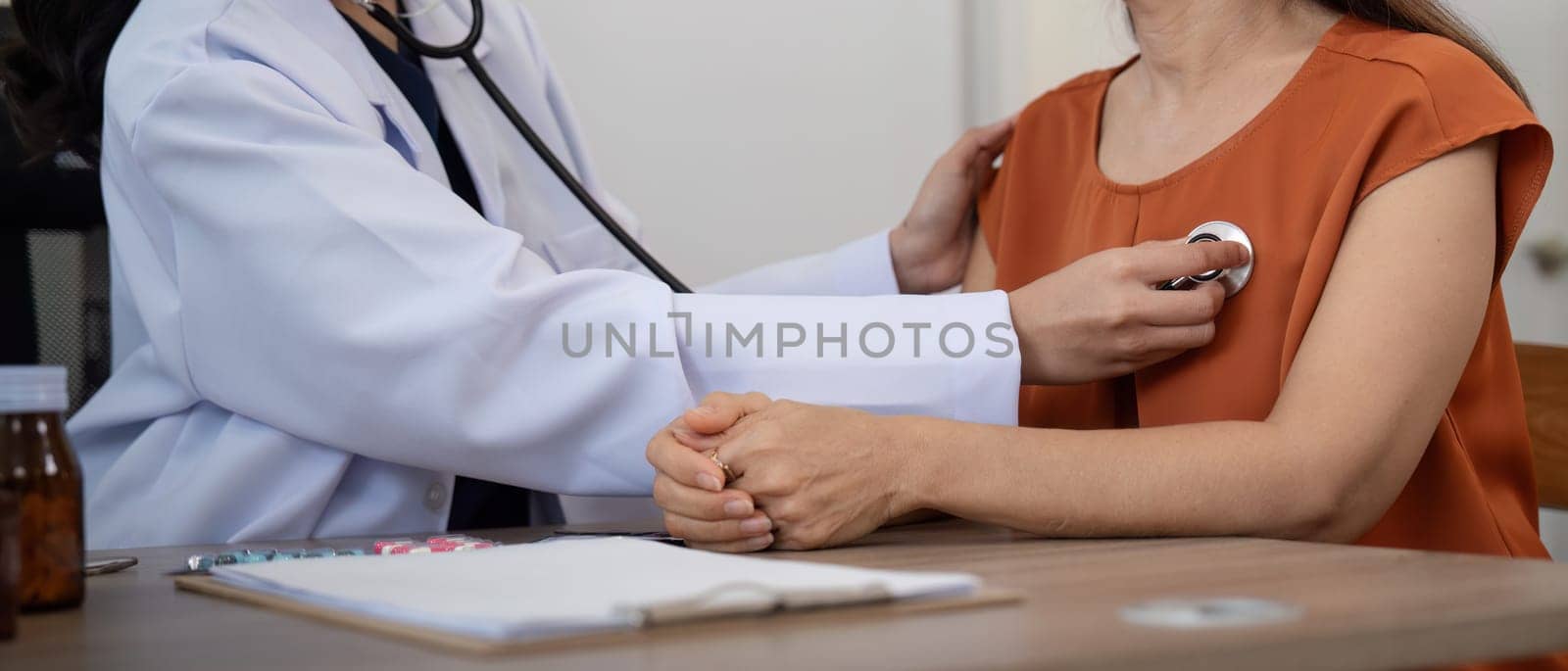 Elderly woman asian patient are check up health while a woman doctor use a stethoscope to hear heart rate. elderly healthcare concept by nateemee
