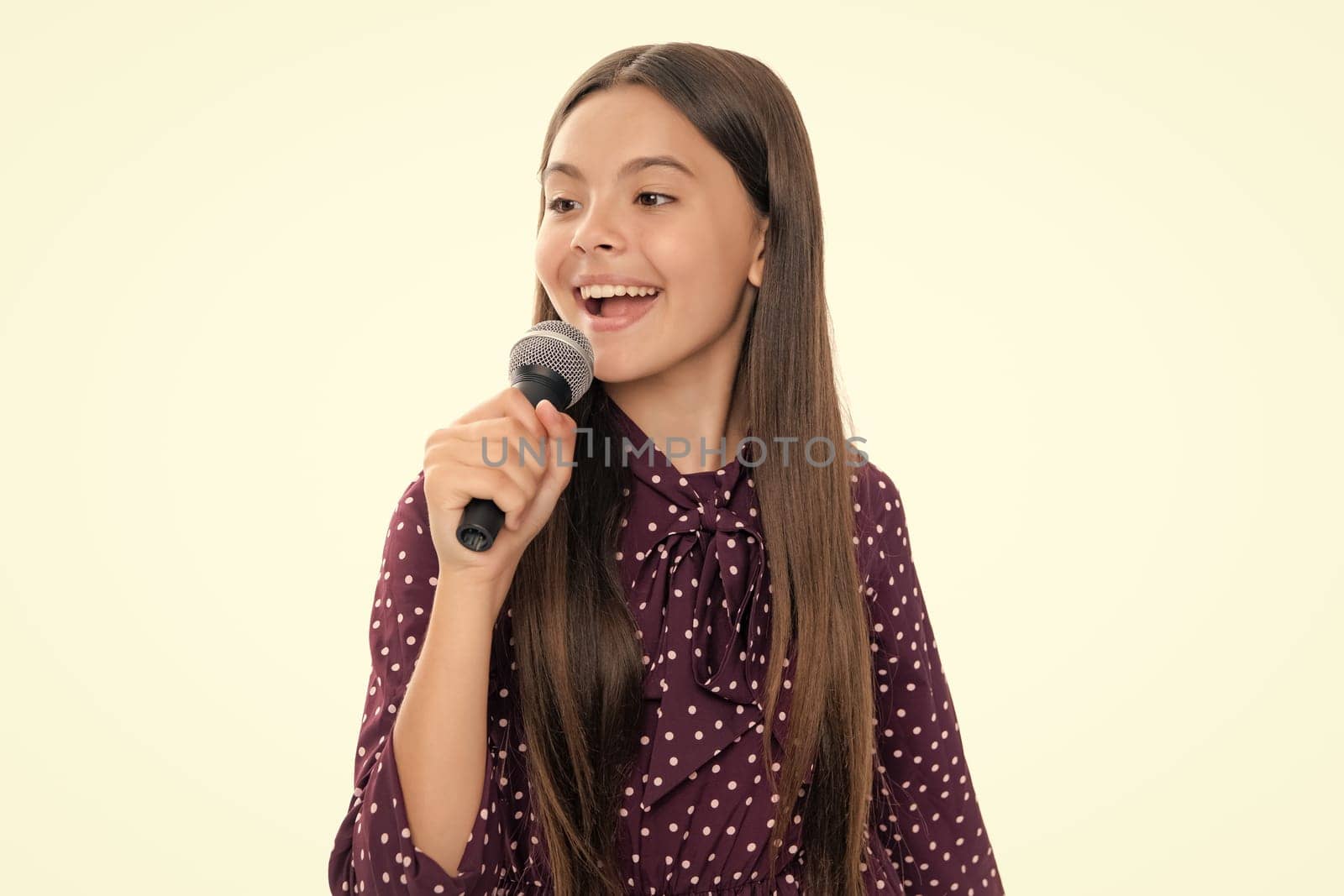 Kid singing. Emotional amazed teen girl with microphone singing against white background. Singing lovely singer girl hold microphone