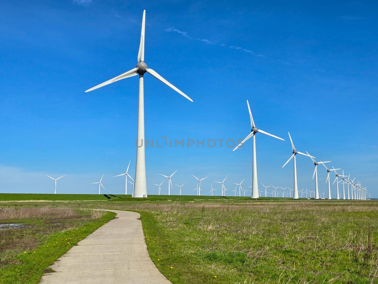 Windmill park in the ocean, view of windmill turbines on a Dutch dike generating green energy electrically, windmills isolated at sea in the Netherlands.