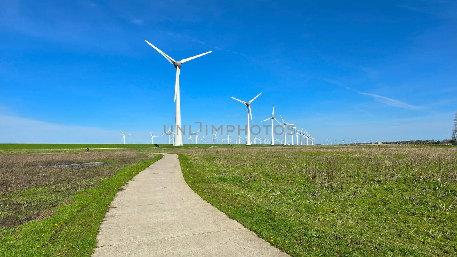 Windmill park in the meadow, view of windmill turbines on a Dutch dike generating green energy electrically, windmills isolated at sea in the Netherlands.