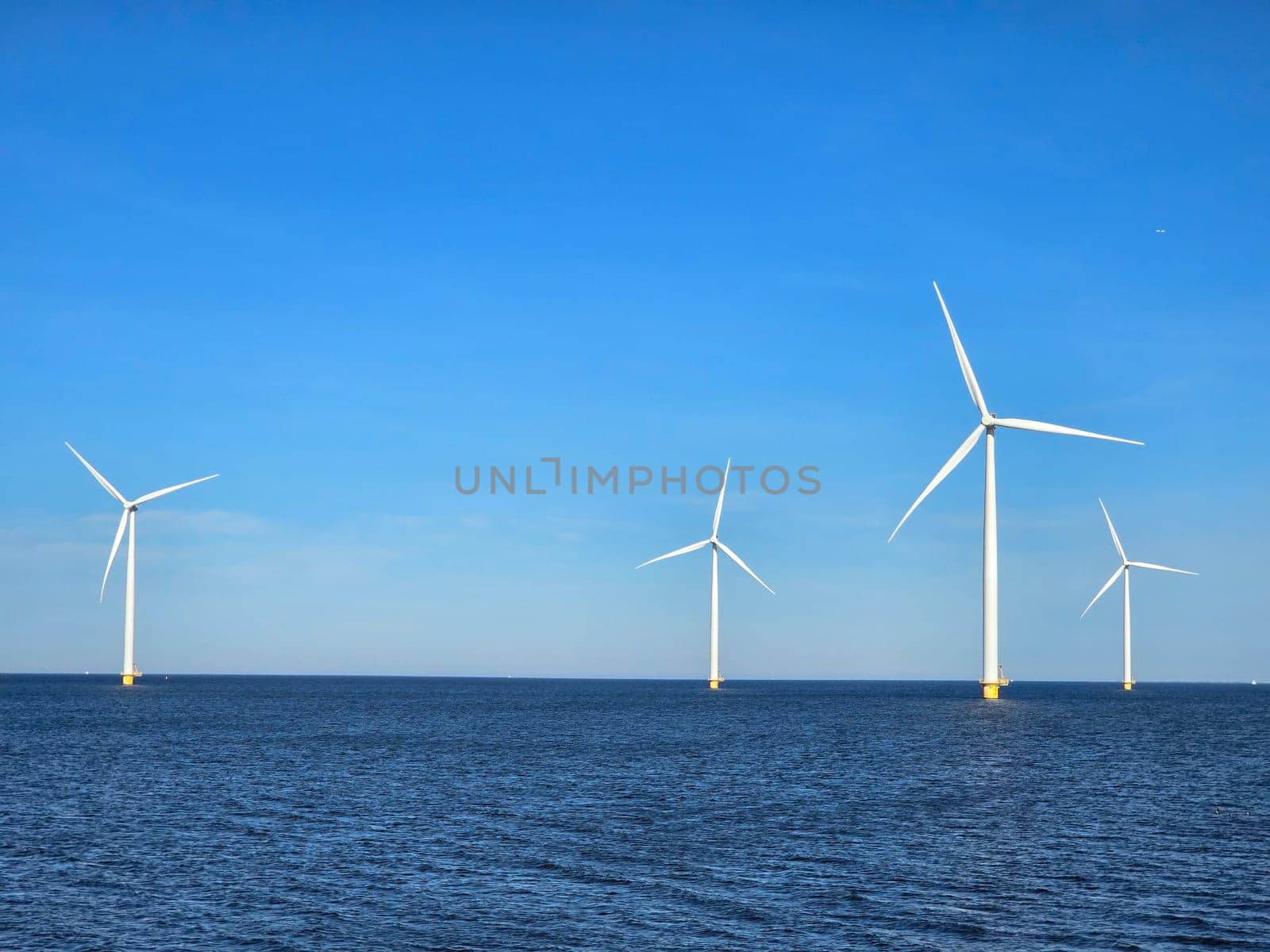 Windmill park in the ocean, Energy transition, zero emissions, carbon neutral, Earth day concept, windmills isolated at sea in the Netherlands.