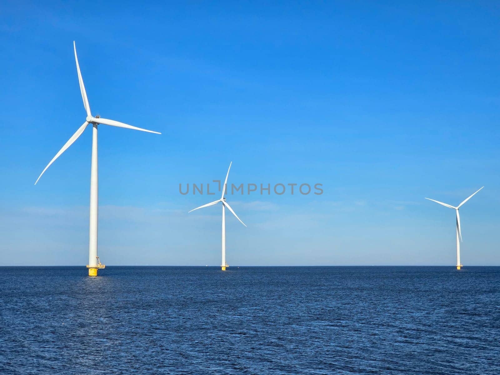 windmill turbines on a Dutch dike generating green energy electrically, windmills isolated at sea in the Netherlands. Energy transition, zero emissions, carbon neutral