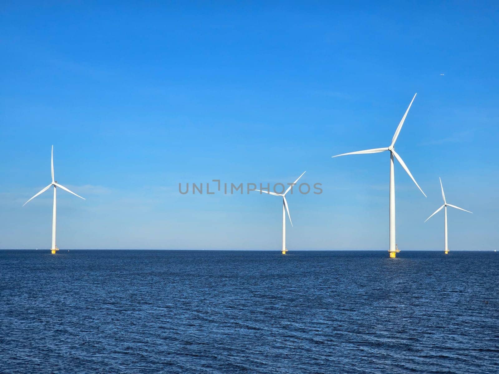 windmill turbines in the ocean generate green energy electrically, and windmills isolated at sea in the Netherlands. Energy transition, zero emissions, carbon neutral, Earth day concept