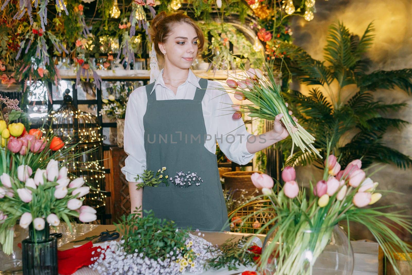 A woman in her florist shop collects bouquets of flowers. The concept of a small business. Bouquets of tulips for the holiday on March 8