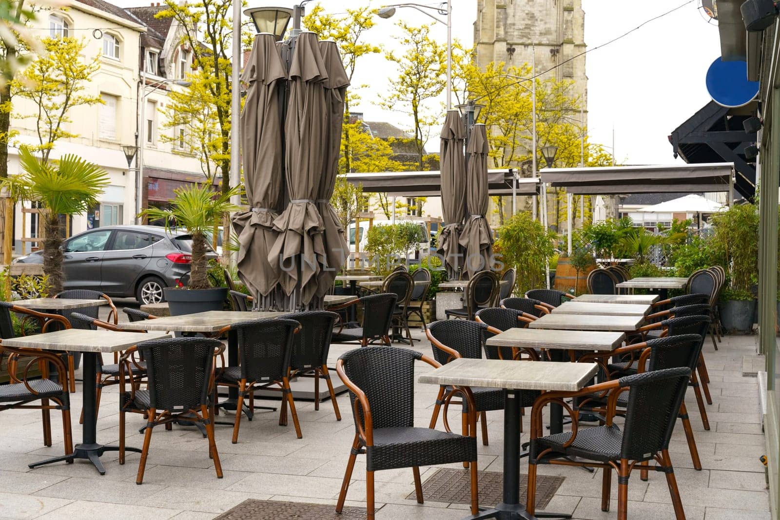 A scene showing a variety of tables, chairs, and umbrellas set up in an outdoor dining area.