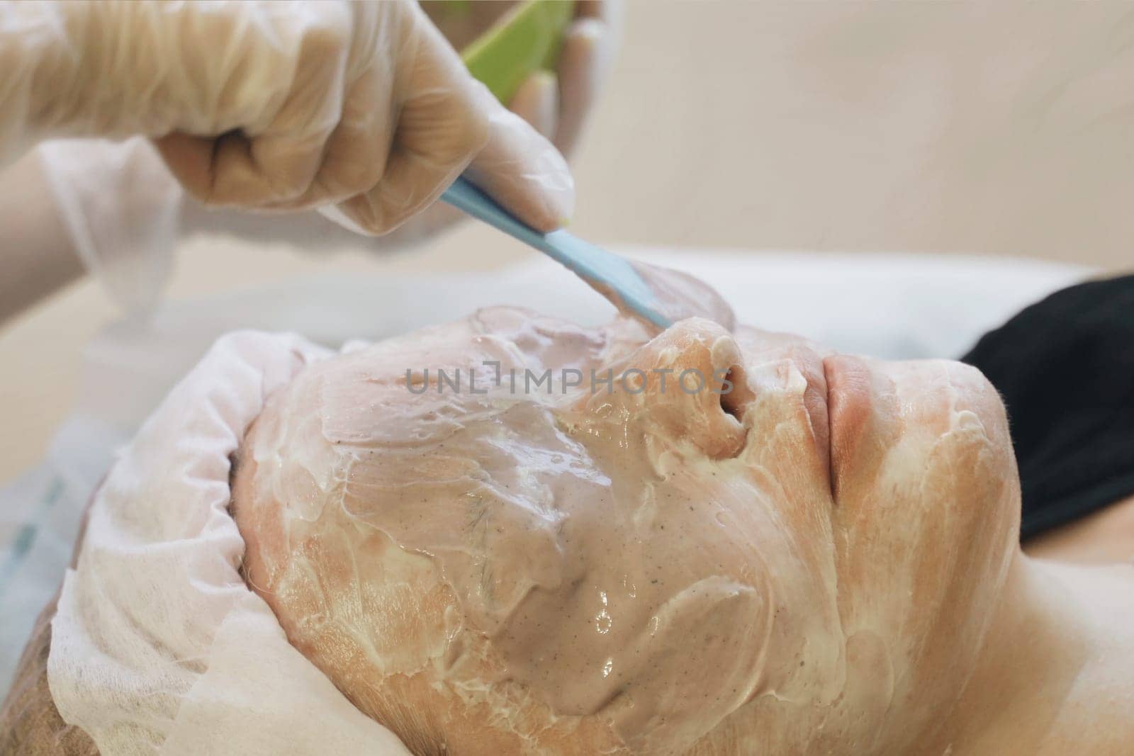 A woman getting a facial mask applied on her face at a beauty salon.