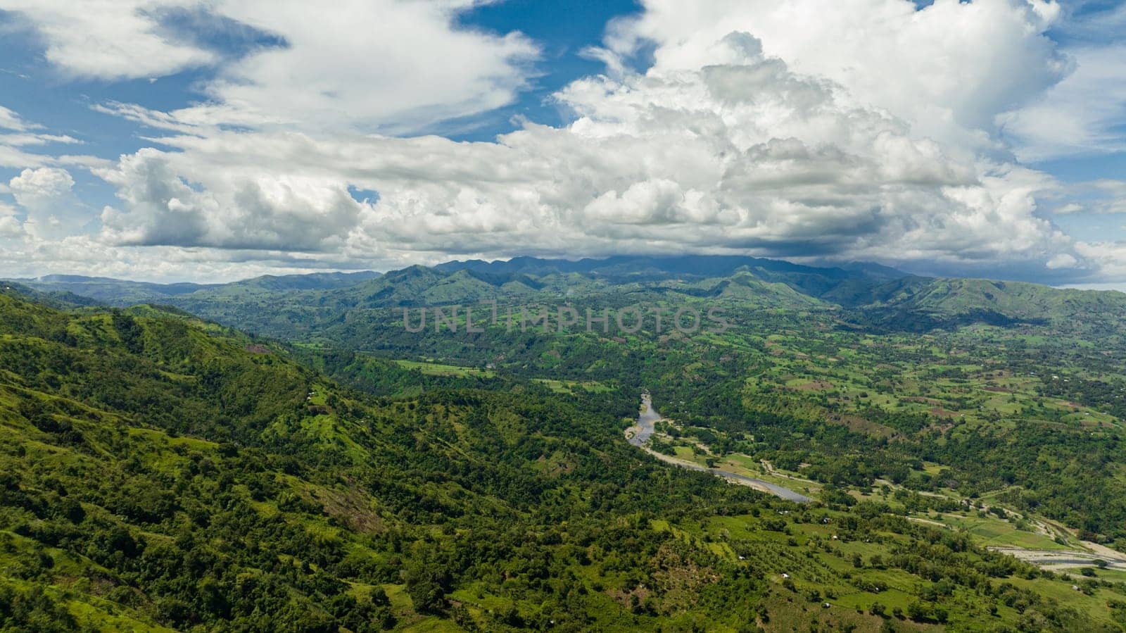Top view of river in a mountain valley among agricultural land and rice fields. Negros, Philippines