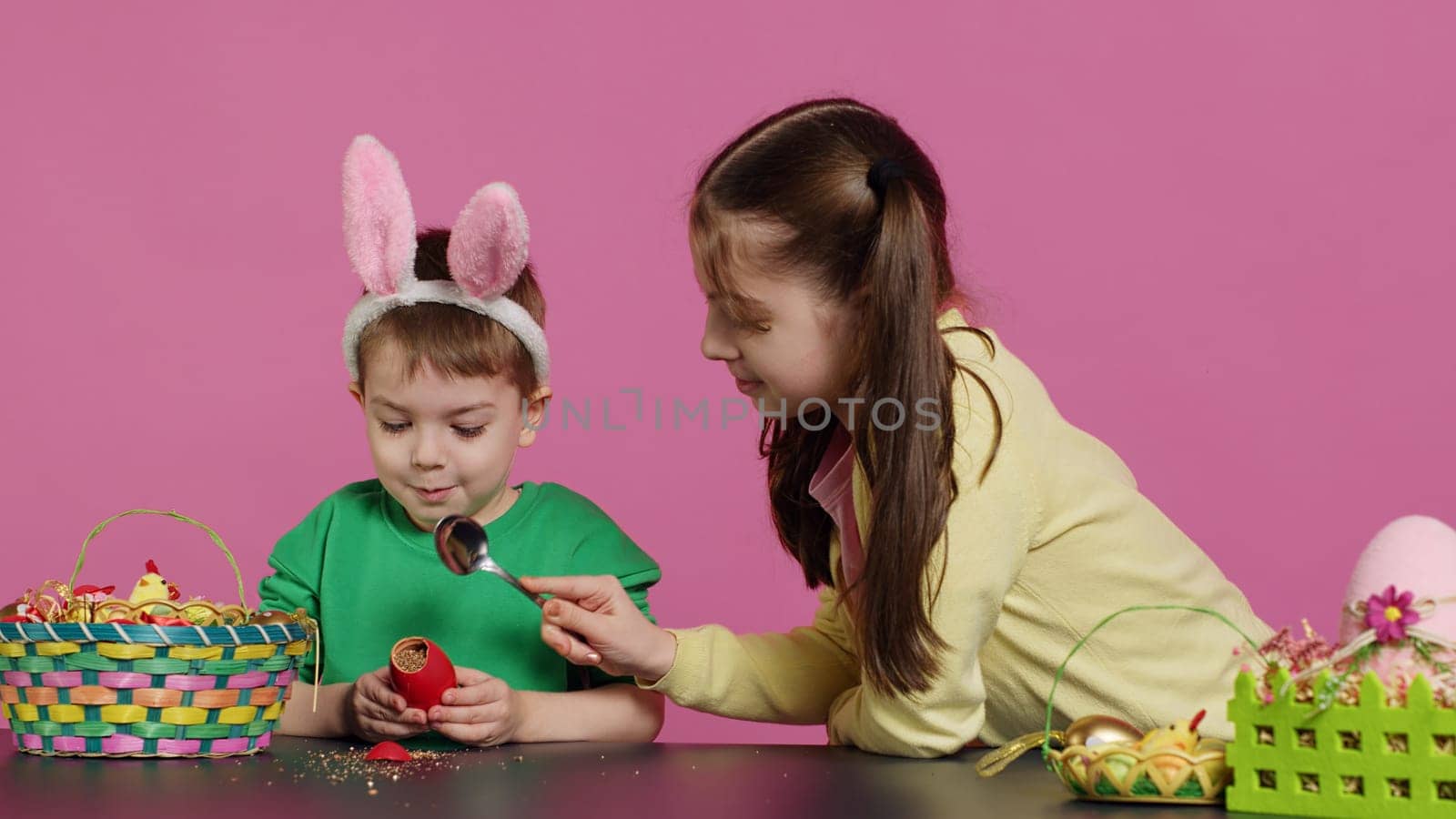 Ecstatic kids breaking a special easter egg to find a surprise inside, feeling curious about a festive decoration that transforms in a plant. Cheerful little children having fun in studio. Camera A.
