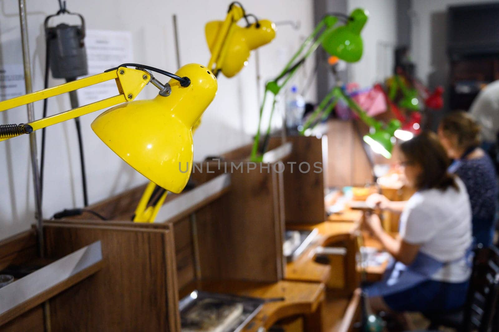 Interior of a busy art workshop with focused participants crafting under bright lamps
