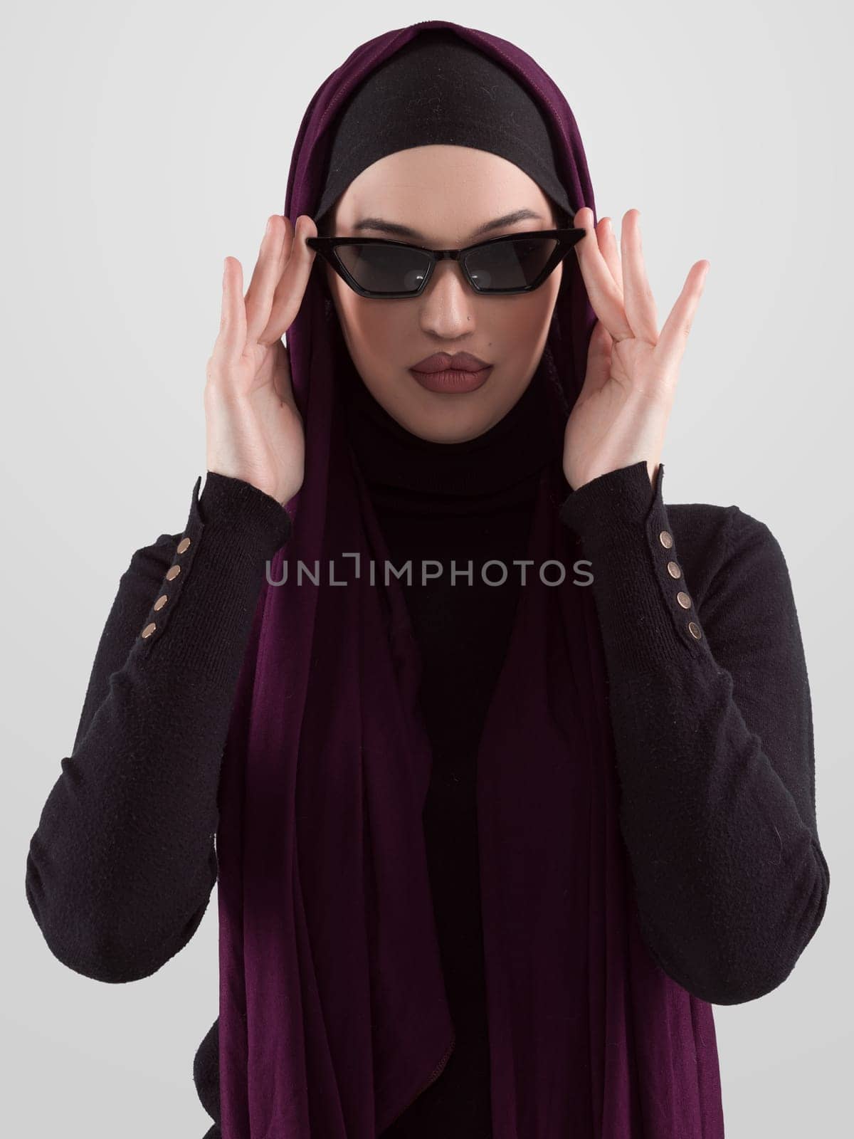 Portrait of beautiful stylish young muslim woman wearing black hijab and sunglasses as modern eastern fashion concept posing on white background. by dotshock