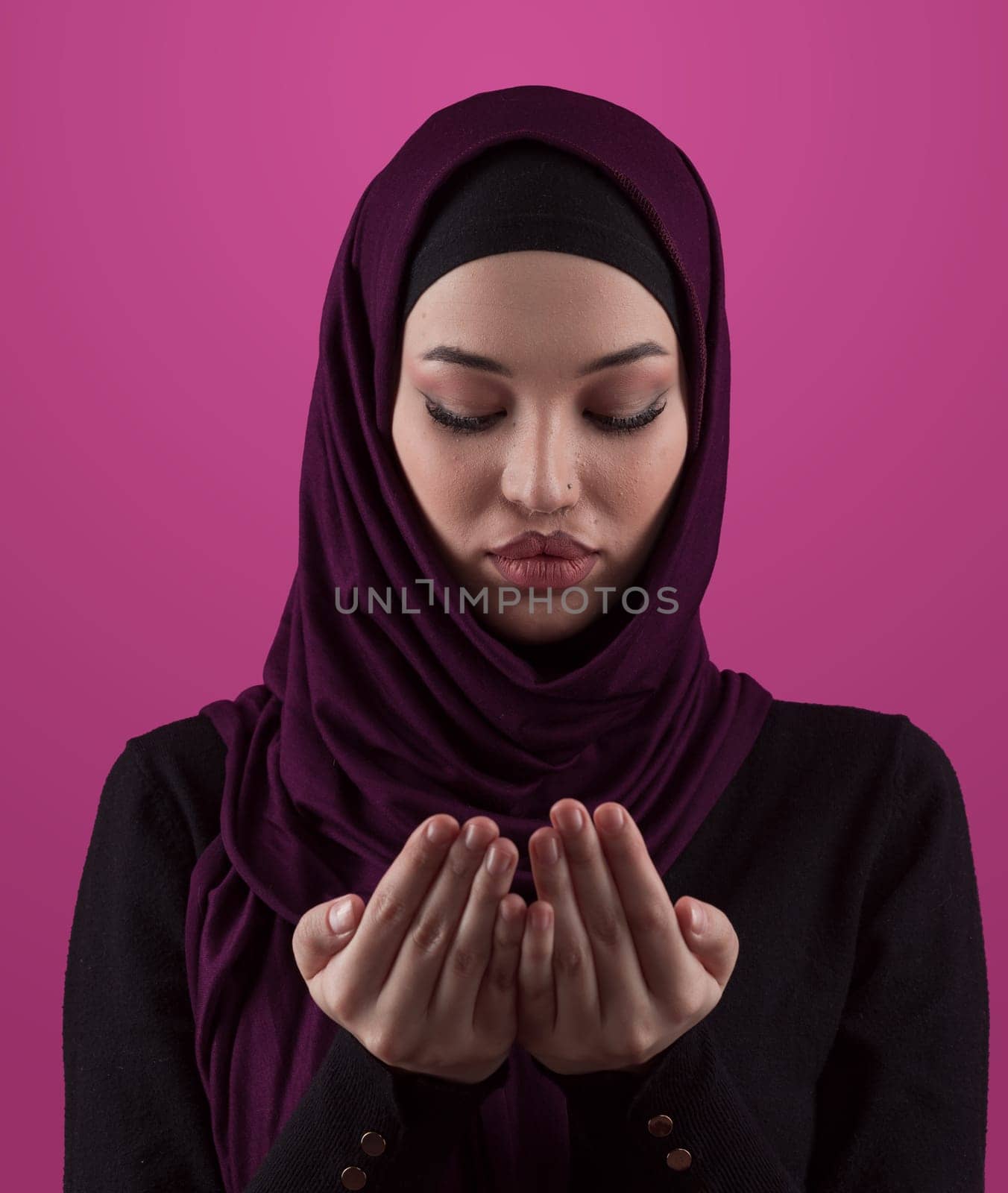 Muslim woman in hijab and traditional clothes praying for Allah, copy space. Muslim woman with hijab praying indoor pink background. by dotshock