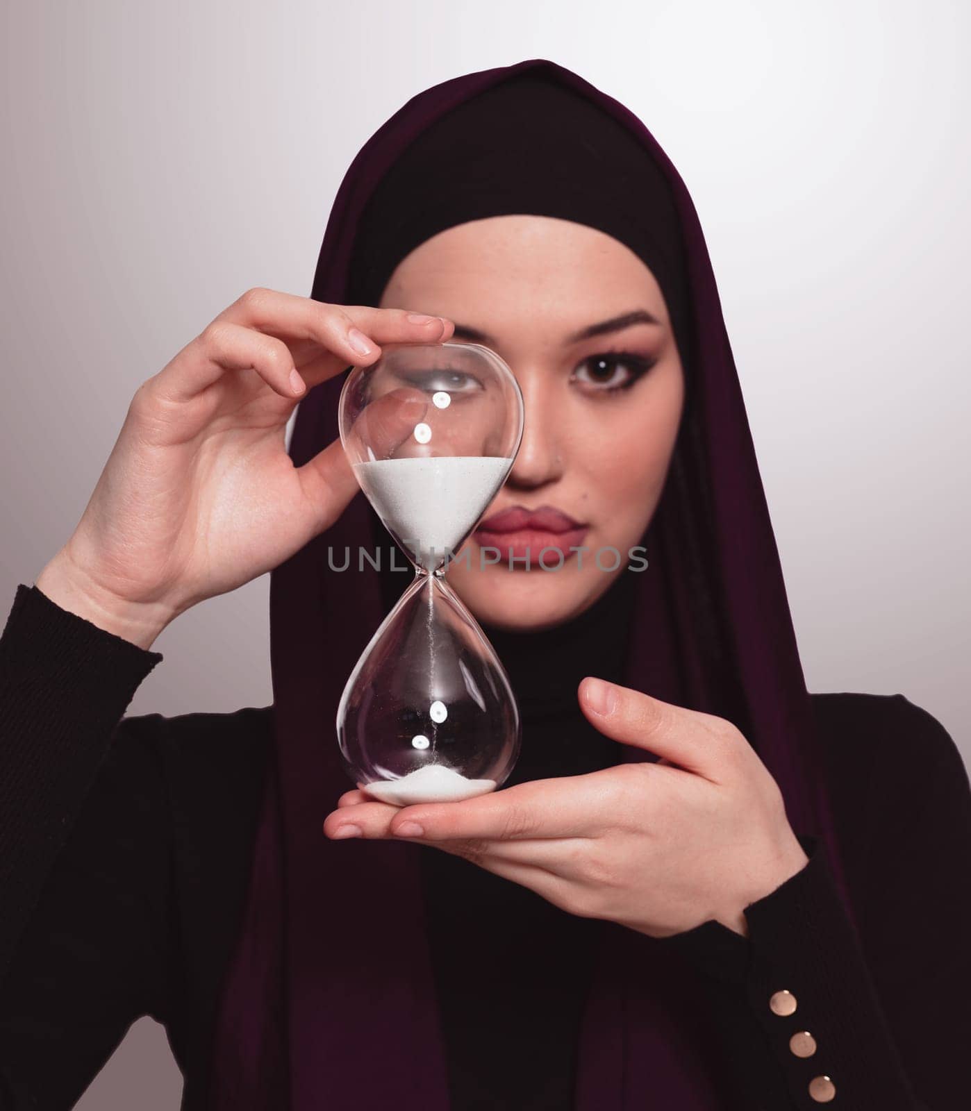 Beautiful arab businesswoman wearing hijab and holding sand clock. Time is passing and it's a pressure concept. High quality photo