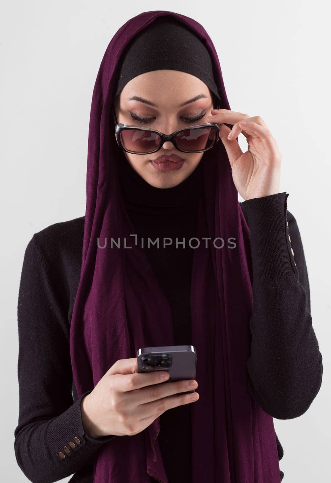 Woman in black stylish fashionable clothes Muslim headscarf. Lady using smart phone, close up portrait of smiling middle eastern girl. by dotshock