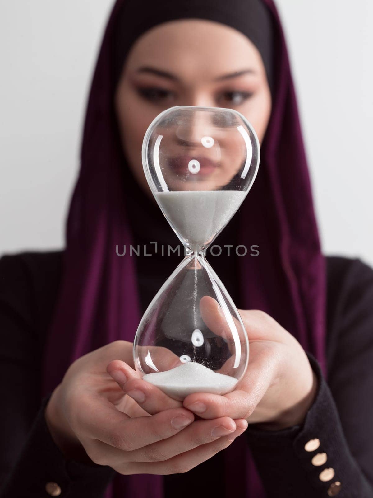 Beautiful arab businesswoman wearing hijab and holding sand clock. Time is passing and it's a pressure concept. High quality photo