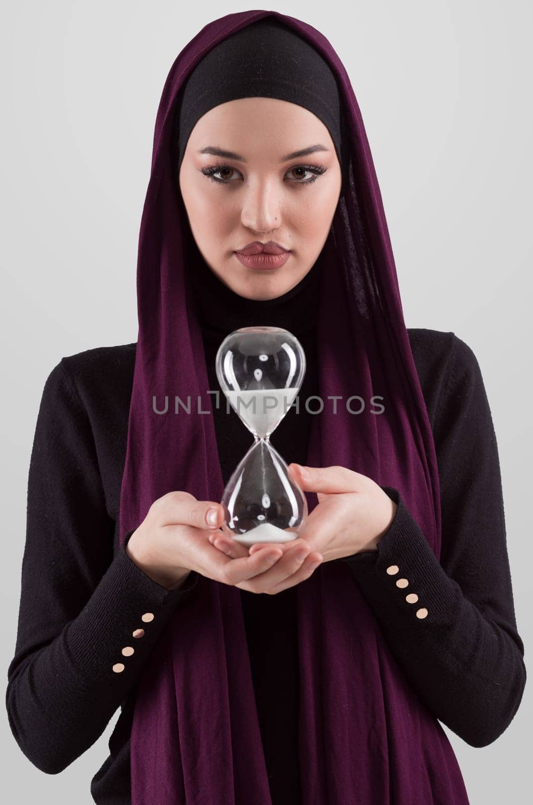 Beautiful arab businesswoman wearing hijab and holding sand clock. Time is passing and it's a pressure concept. High quality photo