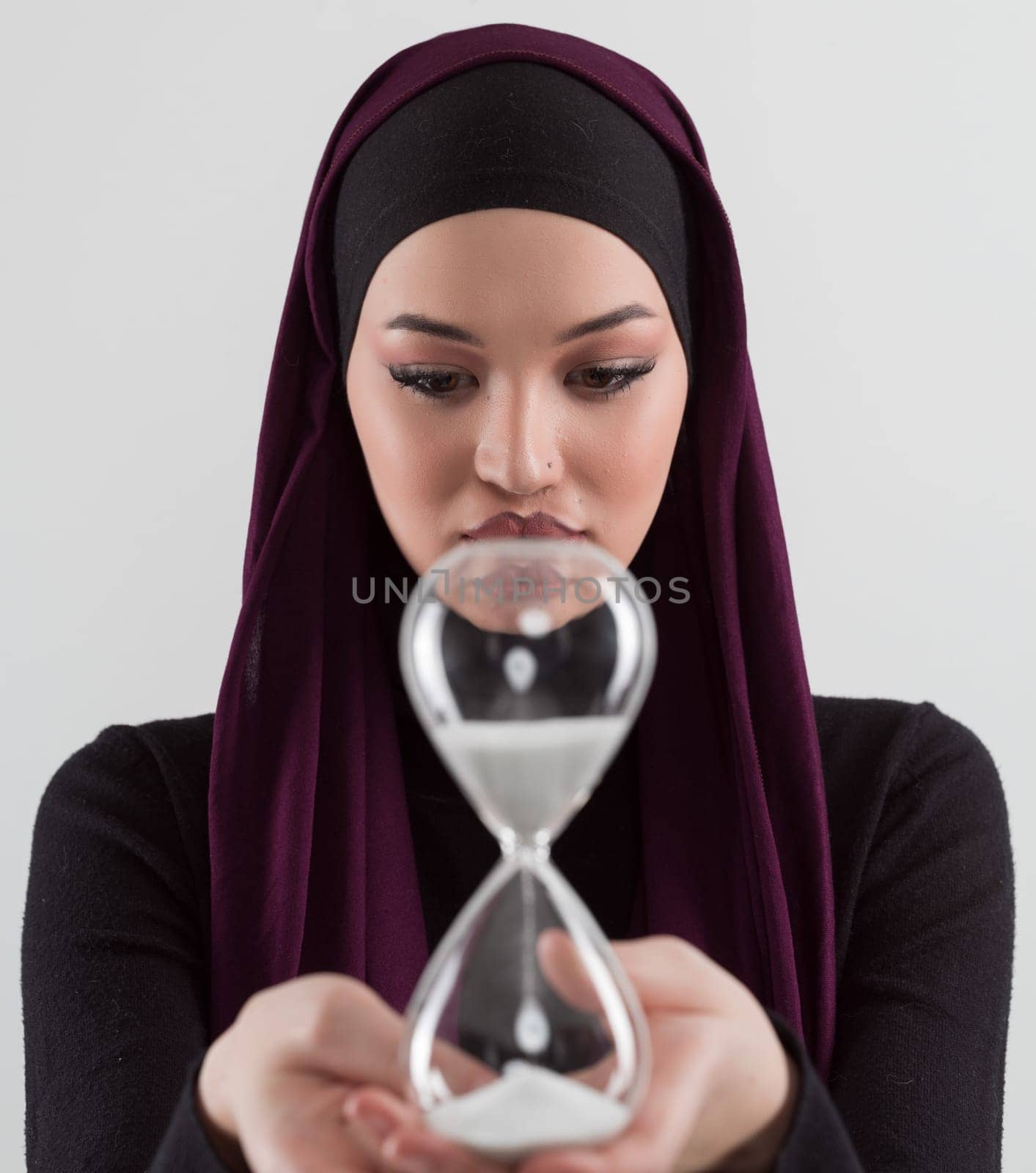 Beautiful arab businesswoman wearing hijab and holding sand clock. Time is passing and it's a pressure concept. by dotshock