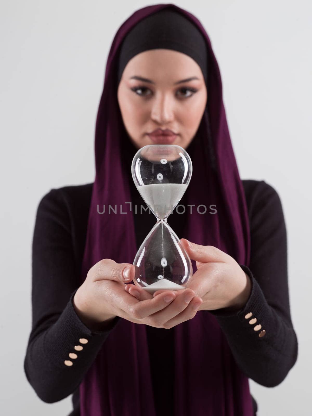 Beautiful arab businesswoman wearing hijab and holding sand clock. Time is passing and it's a pressure concept. by dotshock
