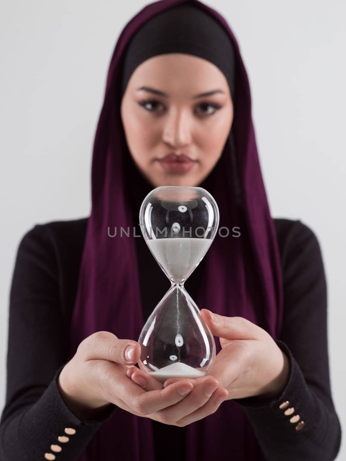 Beautiful arab businesswoman wearing hijab and holding sand clock. Time is passing and it's a pressure concept. by dotshock