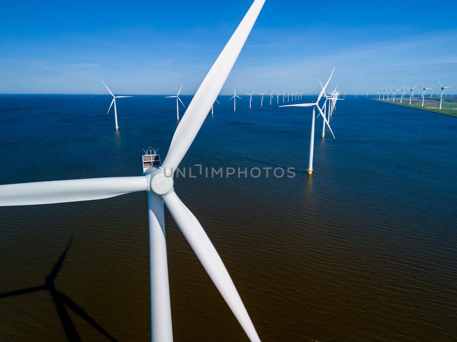 A large group of windmills stands tall in the tranquil waters of Flevoland Netherlands by fokkebok
