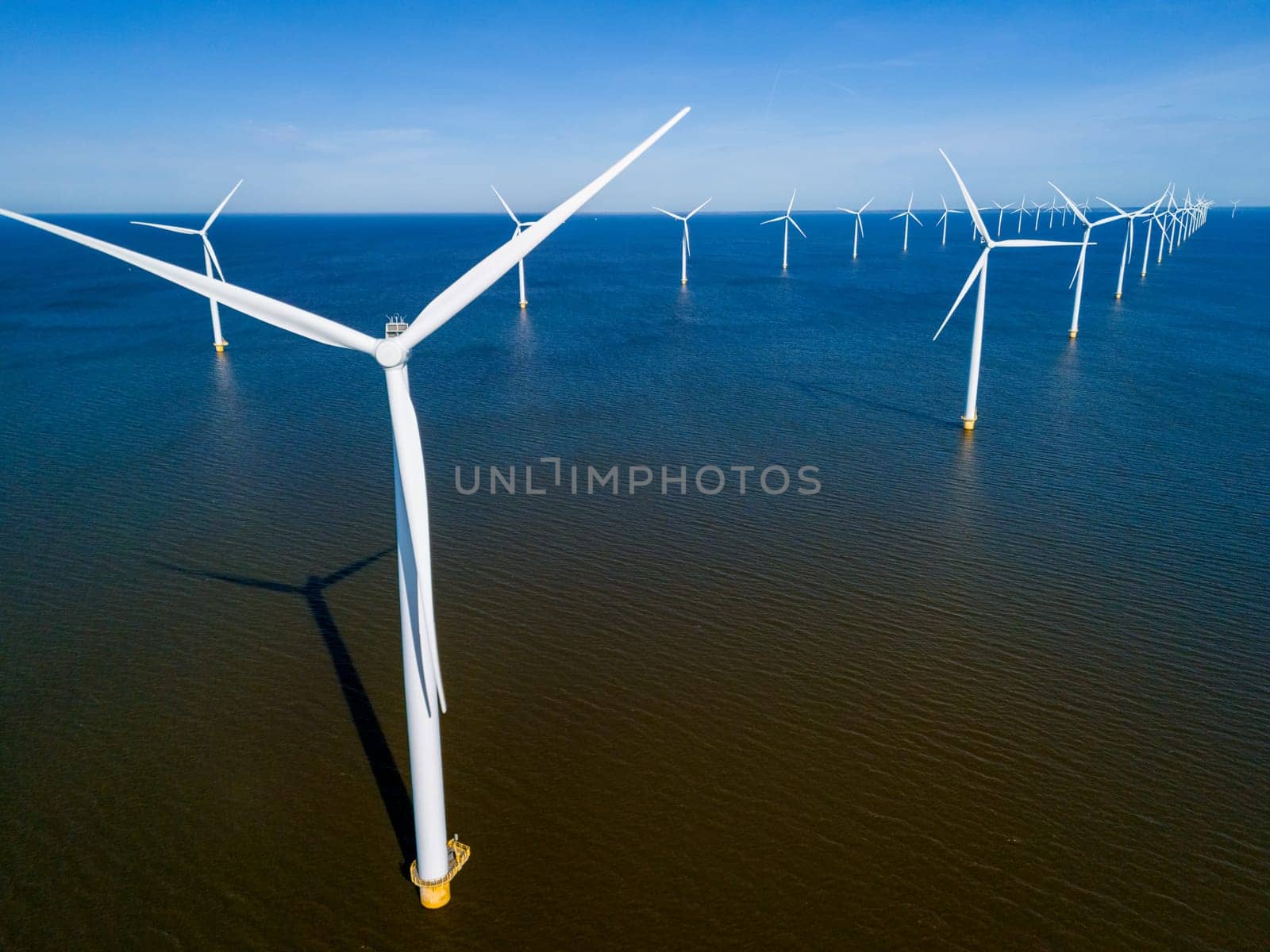 A group of wind turbines majestically spinning in the ocean generate clean and sustainable energy by fokkebok