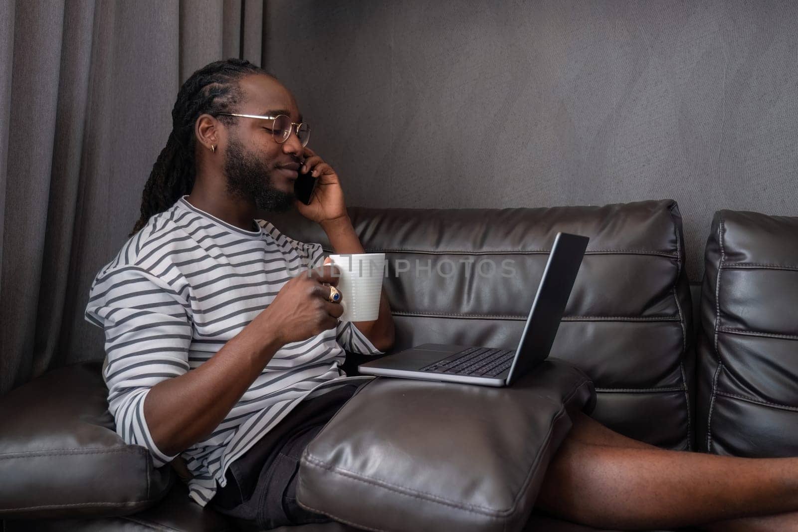 Young African American businessman spends his free time working from home on his laptop..