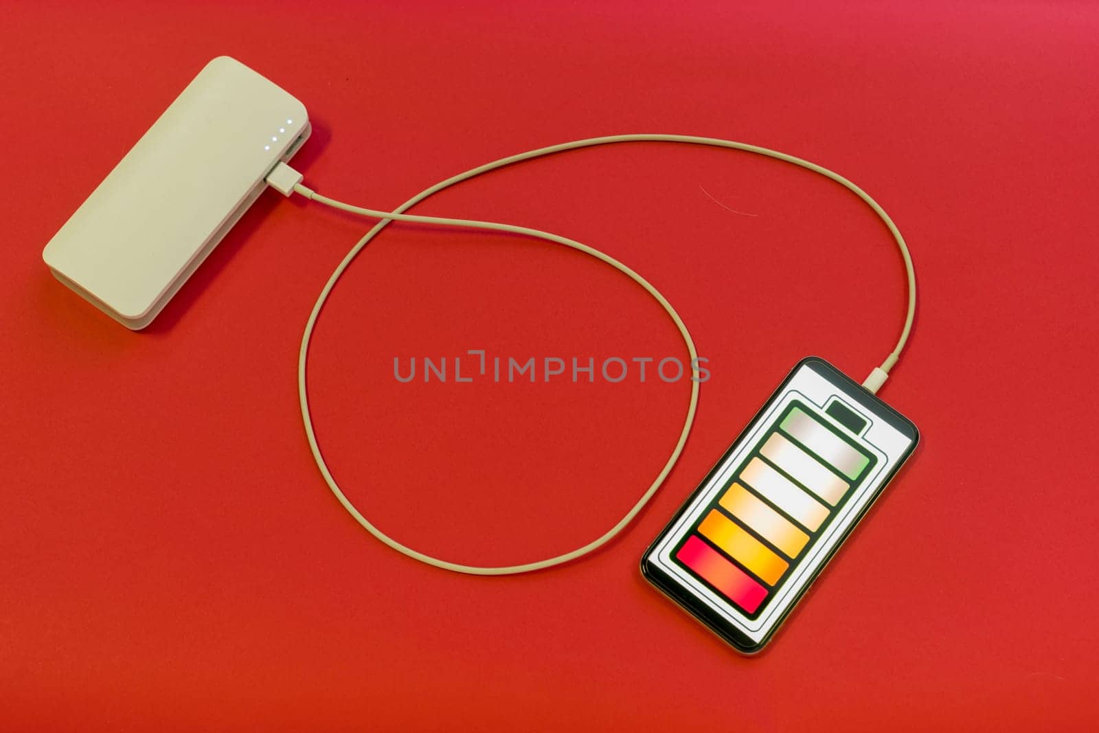 Smartphone is charging with power bank on red background by zartarn