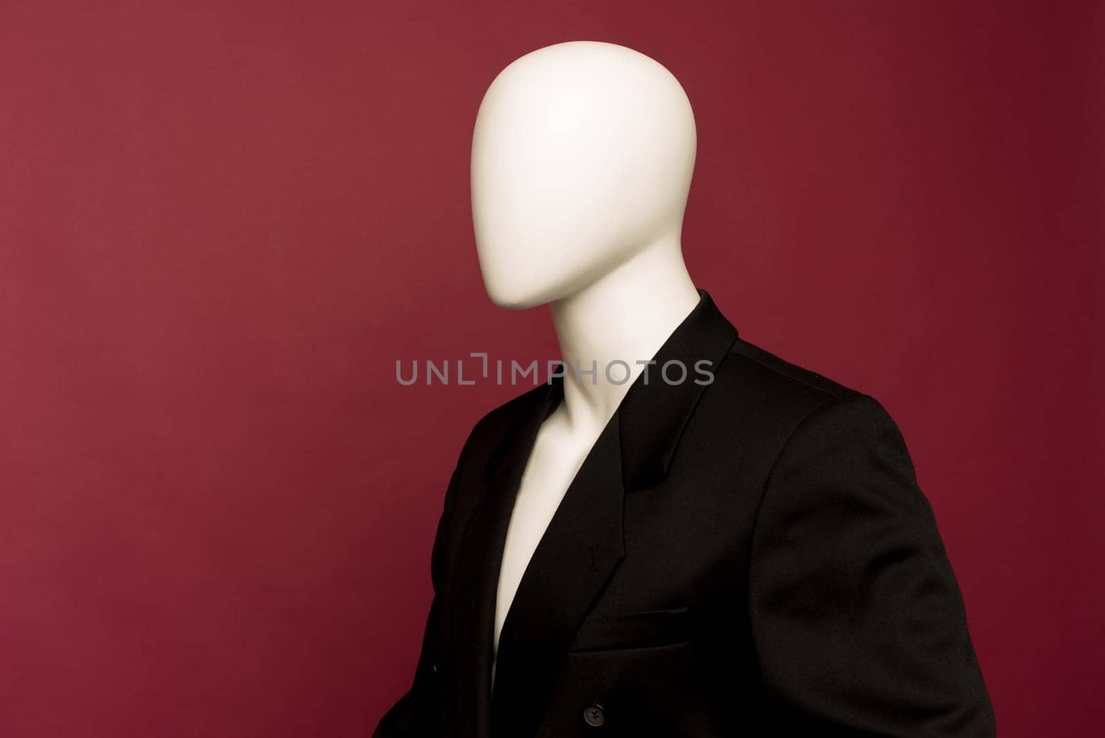 White male mannequin in a black business suit on a ruby background by zartarn