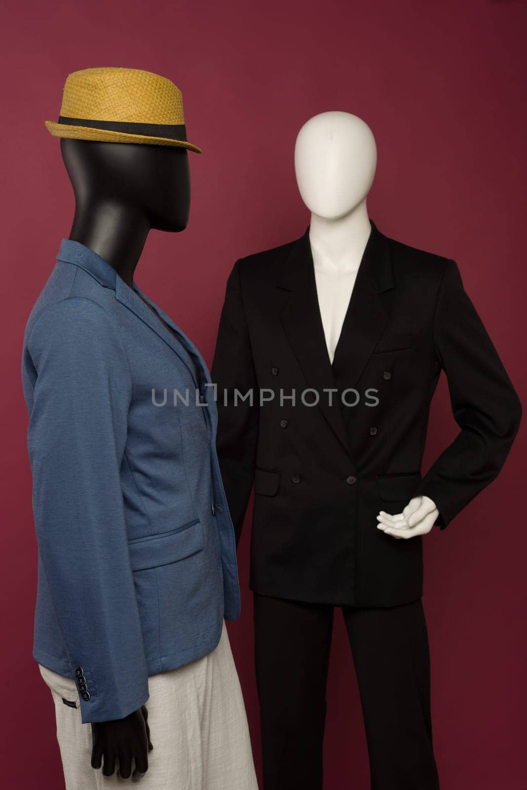 Two male mannequin in a black business suit and in a blue suit and white pants on a ruby background by zartarn