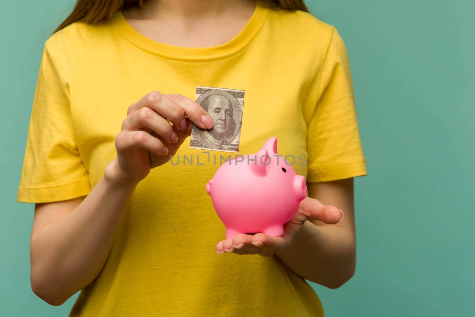 woman hand putting 100 dollars into piggy for saving money wealth and financial concept. by zartarn